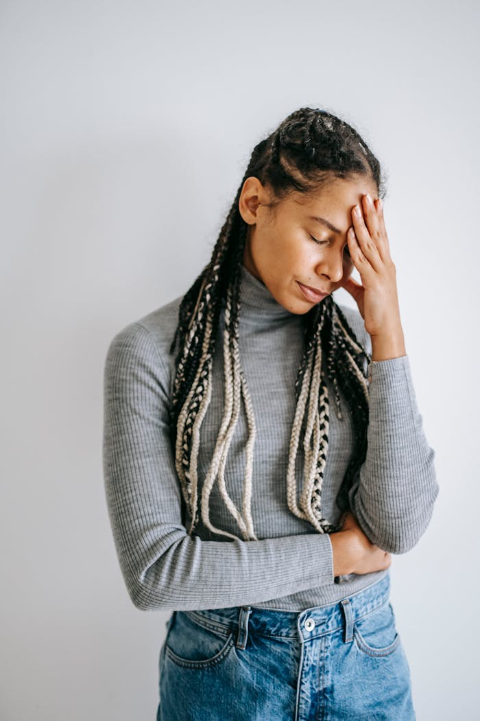 Upset black woman touching head on light background